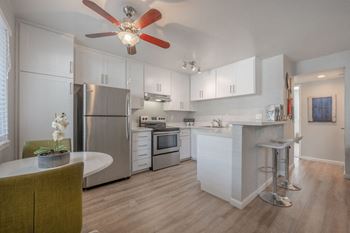 A kitchen with white cabinets and a ceiling fan